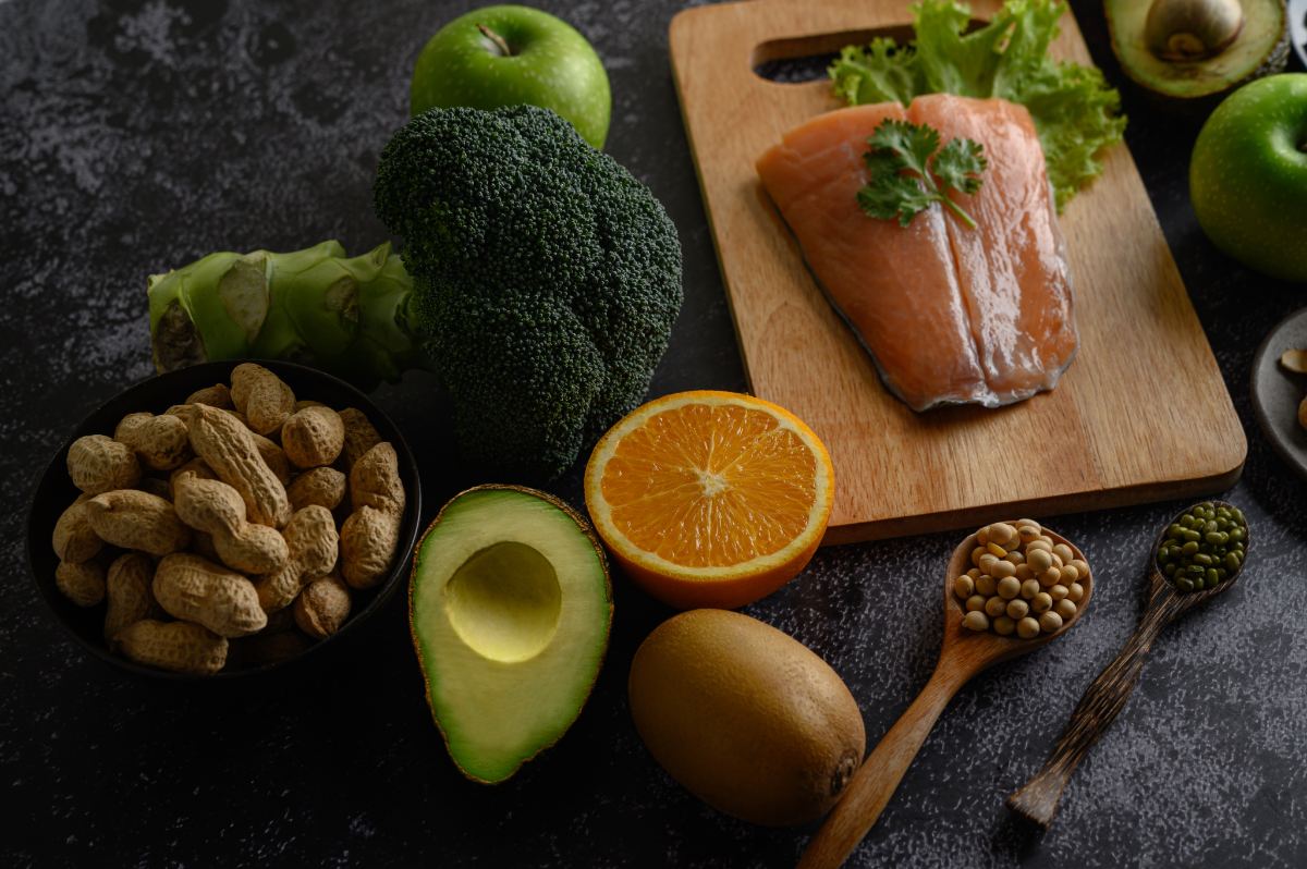Salmon, broccoli, avocado, nuts, kiwi, apples and an orange